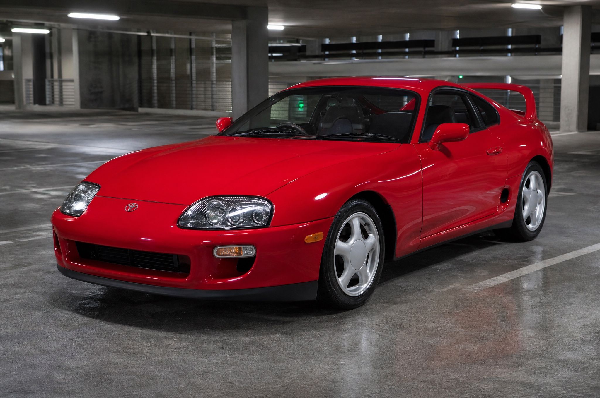 A red Toyota Supra parked in a concrete parking garage