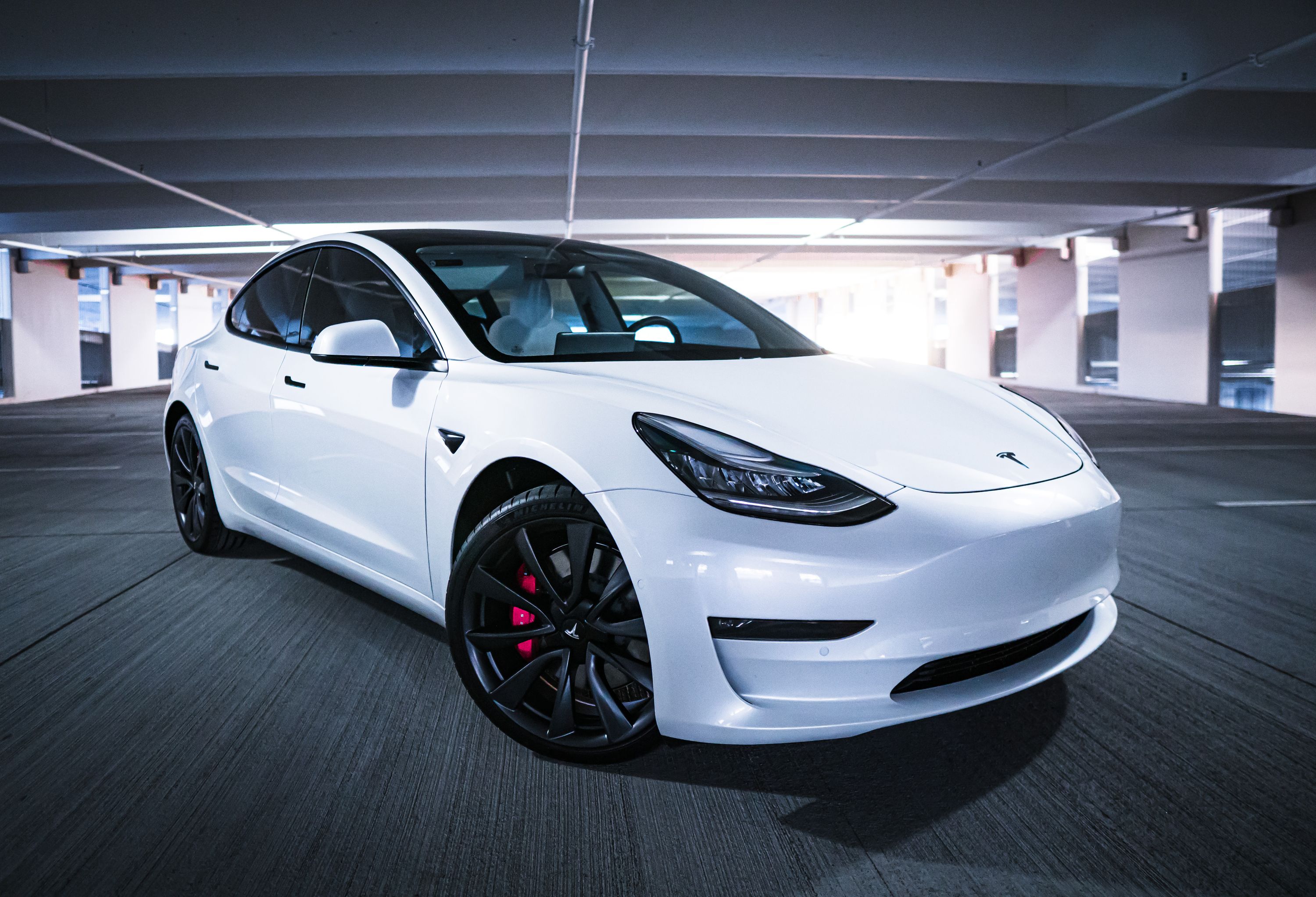 Original white sedan photographed in a parking garage