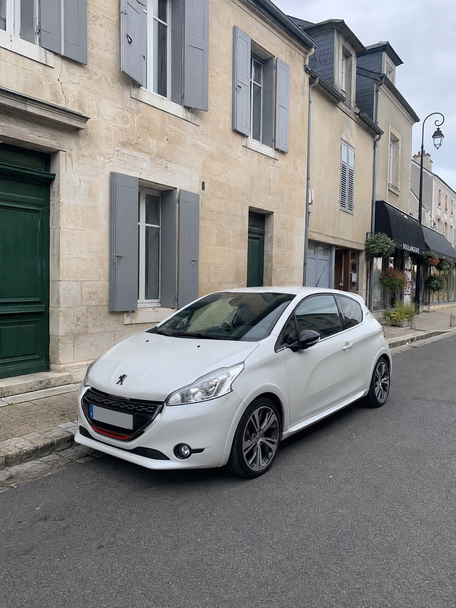 Peugeot 208 GTi blanche d'origine, garée dans une rue française