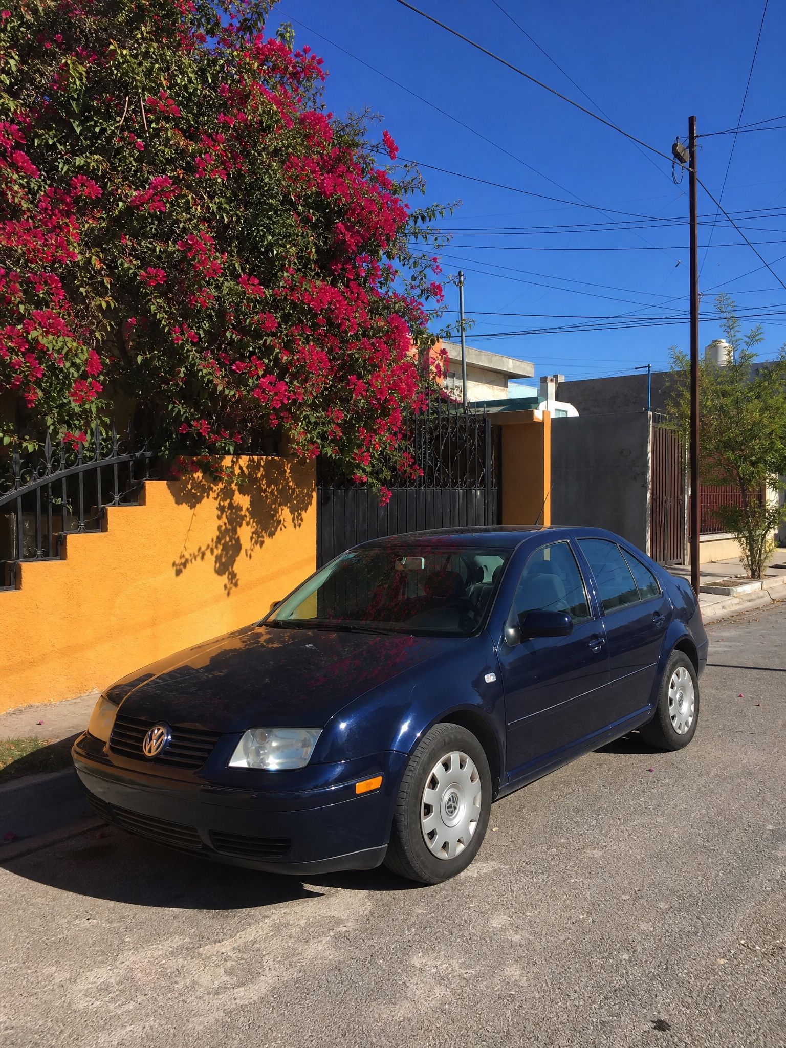 Volkswagen Jetta azul de agencia, con tapones originales, estacionado en la calle